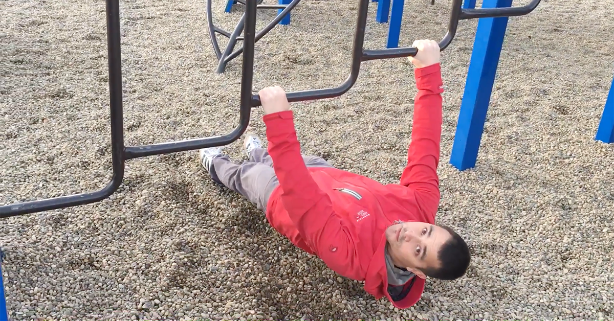 Man doing an Australian pull-up on a playground.